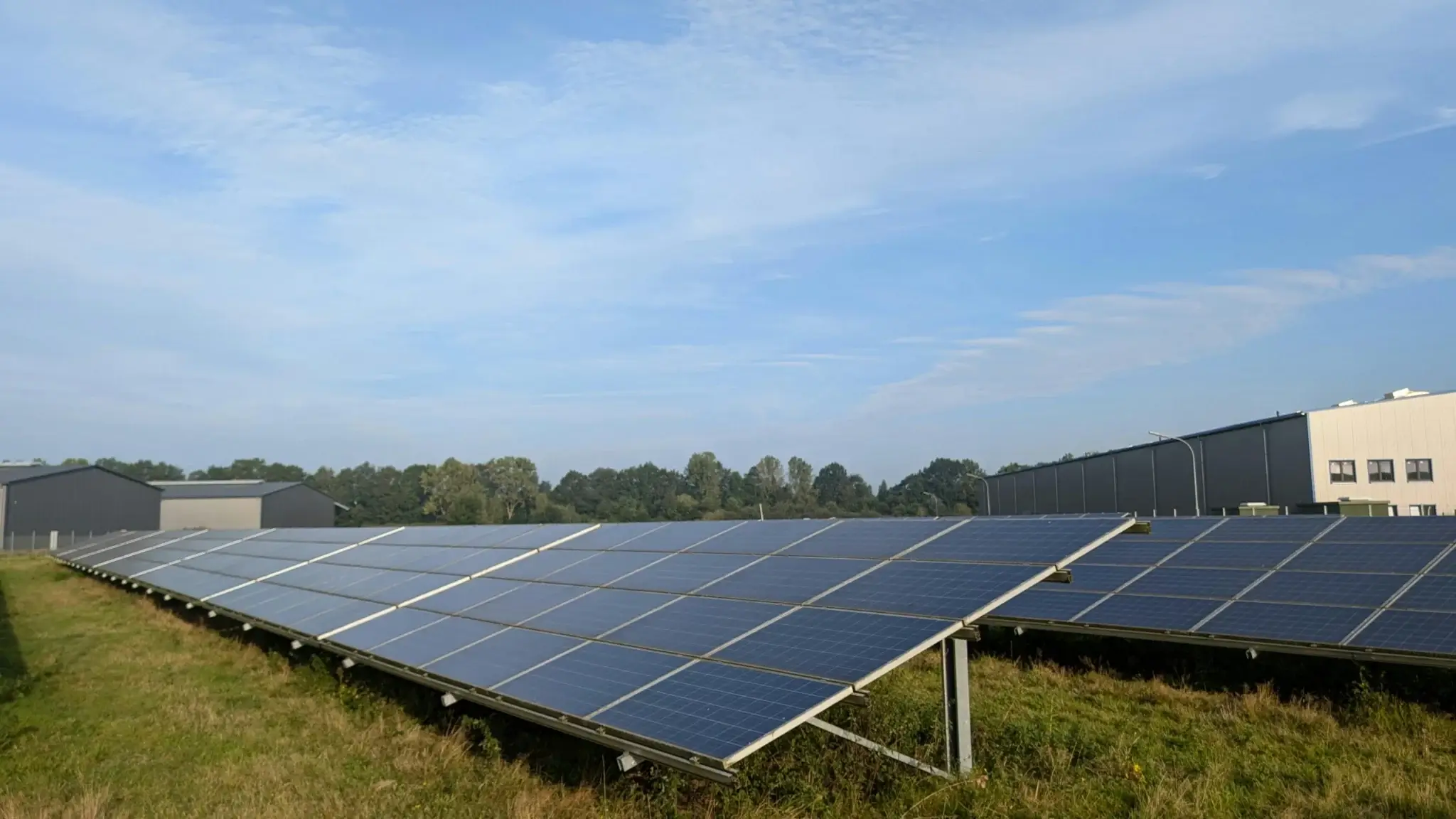 Photovoltaikanlage auf Freifläche neben Industriegebäude – Photovoltaik Projektentwicklung